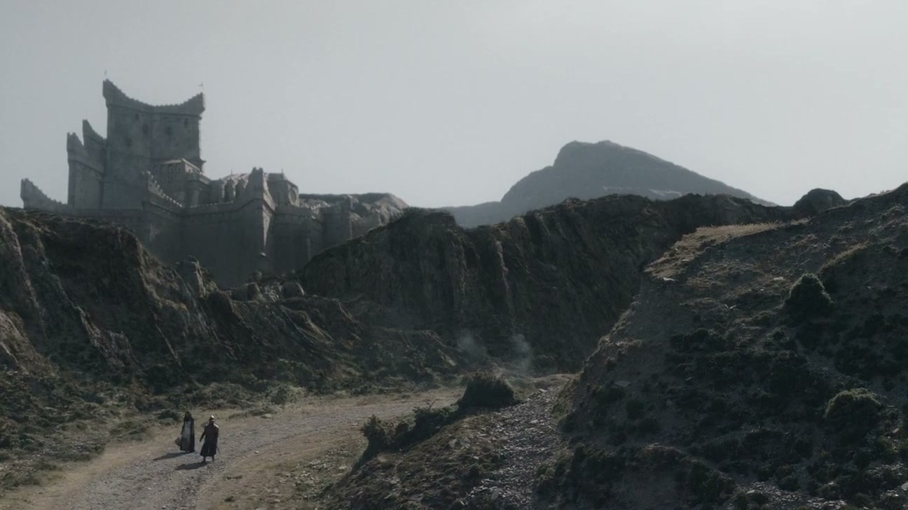 A castle on a crag above a road through a rocky gorge